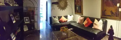 a living room with a black leather couch with pillows at La Casa de mi Abuelo in Cusco