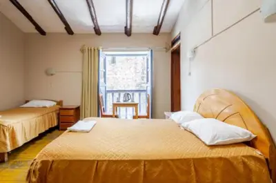 a hotel room with two beds and a window at Vista al Qoricancha - 2 cuadras de la Plaza in Cusco
