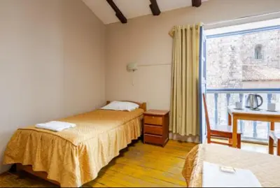 a hotel room with two beds and a balcony at Vista al Qoricancha - 2 cuadras de la Plaza in Cusco