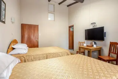 a hotel room with two beds and a flat screen tv at Vista Qoricancha - 2 cuadras Plaza Principal in Cusco