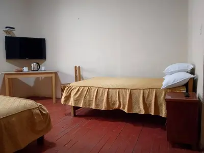 a bedroom with a bed and a desk with a tv at Frente al Qorikancha - 2 cuadras Plaza Central in Cusco