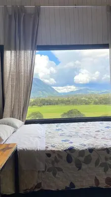 a bedroom with a large window with a view at Cabaña2 con hermosa vista al valle in Oxapampa