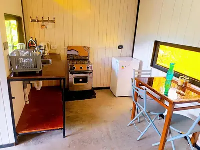 a kitchen with a table and a stove and a refrigerator at Cabaña2 con hermosa vista al valle in Oxapampa
