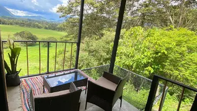 a balcony with chairs and a table and a view at Cabaña2 con hermosa vista al valle in Oxapampa