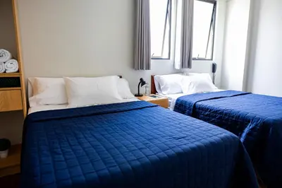two beds in a room with blue comforters at San Miguel Awanka Hotel in Lima