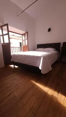 a bedroom with a large bed with a wooden floor at Antuquita's House in Cusco