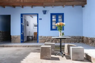 a table in front of a blue wall with a vase of flowers at Quinta San Blas by Ananay Hotels in Cusco