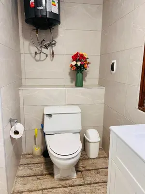a bathroom with a toilet and a vase of flowers at MONTERRICO POLO APARTS #8 - Dpto de 2 camas Frente Embajada de USA con AC in Lima