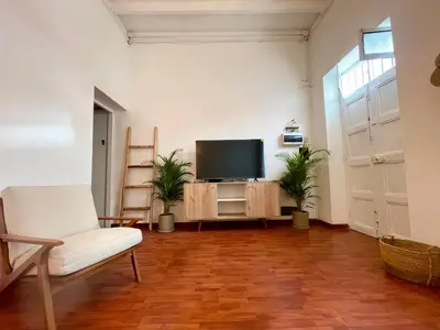 a living room with a tv and a white chair at Entire House close to the sea Miraflores in Lima