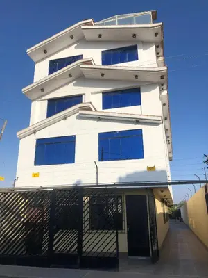 a tall white building with blue windows at Hospedaje Monumental in Chincha