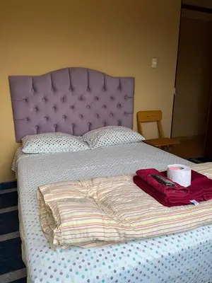 a bed with a purple headboard and a cup on it at Hospedaje Monumental in Chincha