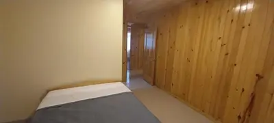 a room with a bed and wooden walls at Cabañas de casa hospedaje Mirador l in Oxapampa
