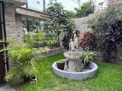 a garden with a fountain in the grass with plants at Casa Extremadura in Lima