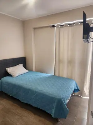 a bedroom with a bed with a blue blanket and a window at Apartamento en Lima in Lima