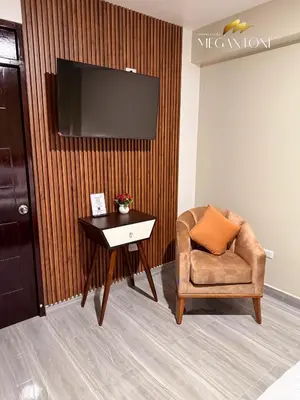 a room with a chair and a table and a television at Grand Hotel Megantoni in Quillabamba
