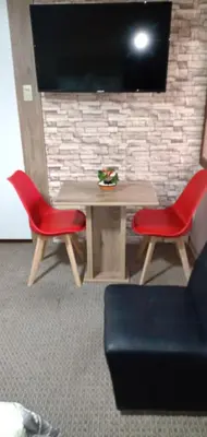 a table with two red chairs and a television at Habitación A1 Trabajar Kitchenette y baño privado in Lima