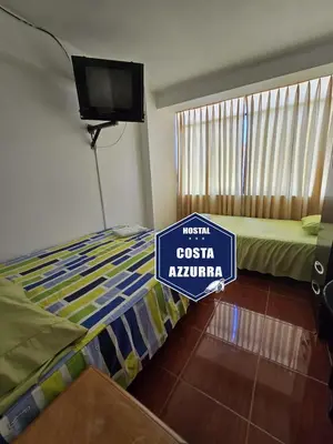 a room with a bed with a sign on it at Hostal COSTA AZZURRA in Cerro Azul