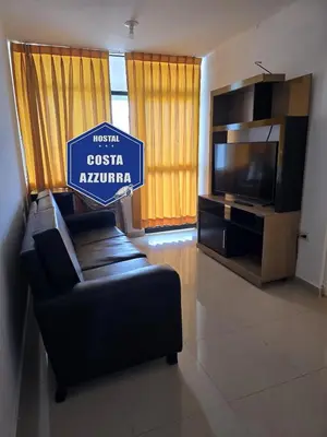 a sign in a living room with a couch and a tv at Hostal COSTA AZZURRA in Cerro Azul