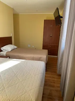 a hotel room with two beds and a television at HOTEL SAMANAHUASi in Nazca