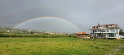 a rainbow over a house in a field with a yard at Casa isaaleya in Cusco