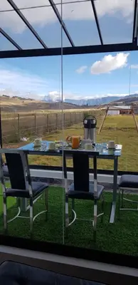 a table and chairs in front of a large window at Casa isaaleya in Cusco