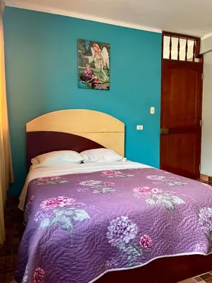 a bedroom with a bed with a purple blanket at Hostal Wassiki in Huánuco