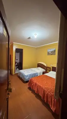 two beds in a room with yellow walls at Hostal Wassiki in Huánuco