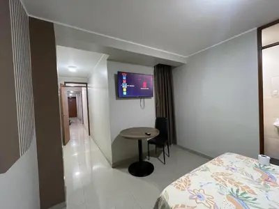 a room with a bed and a table and a tv at Agora Hs in Chincha