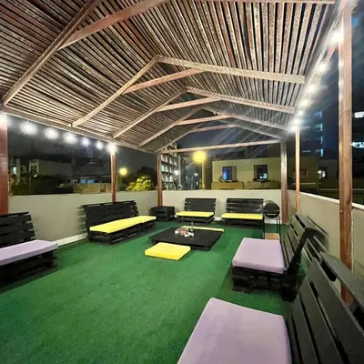 a room with a green floor with benches and tables at Hostel rivendell lima in Lima