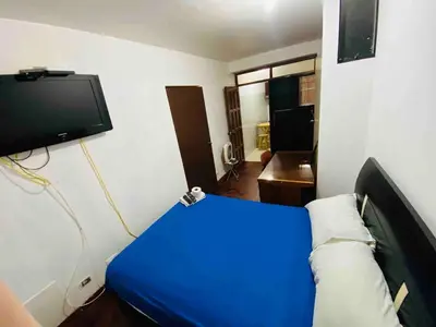 a room with a blue bed and a tv at Minidepartamento La Molina Junin 1 in Lima