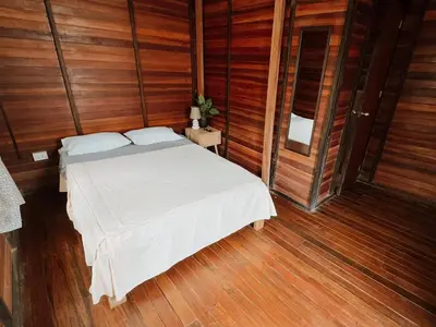 a bedroom with a white bed with wooden walls at HOSPEDAJE CasaBlanca Huacachina in Ica