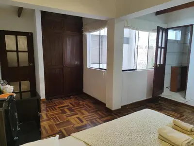 a living room with wooden floors and windows and a room at Amplia habitación independiente con baño privado in Lima