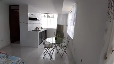 a small white kitchen with a table and chairs in it at Comfortable stay in Los Olivos in Lima
