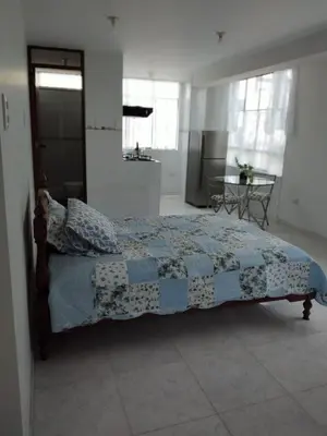 a bedroom with a bed with a blue and white quilt at Comfortable stay in Los Olivos in Lima