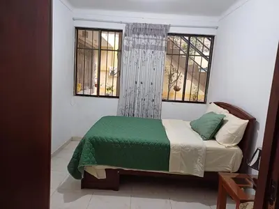 a bedroom with a bed with a green comforter and two windows at Family accommodation in Lima