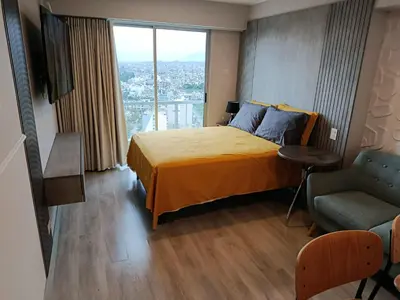 a bedroom with a bed and a chair and a window at LA POSADA DE GUILLE - JAVIER PRADO Este 1501 in Lima