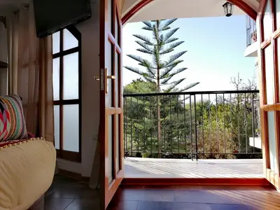 an open door to a balcony with a pine tree at Casa Munayki in Ayacucho
