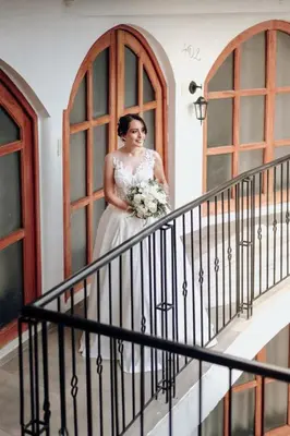 a bride standing on a staircase holding a bouquet at Casa Munayki in Ayacucho