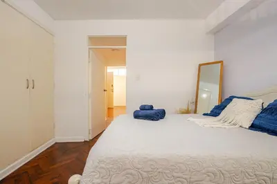 a white bedroom with a large bed with a mirror at Mini depa en el corazón de Miraflores in Lima