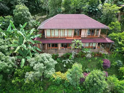 a house with a red roof in a garden at Waranway Lodge Huayopata in Quillabamba