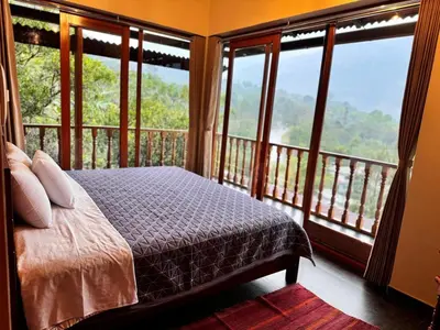 a bedroom with a bed and a balcony with windows at Waranway Lodge Huayopata in Quillabamba