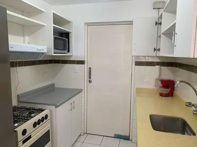 a small kitchen with white cabinets and a sink at Departamento en Miraflores in Lima