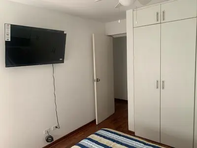 a bedroom with white cabinets and a flat screen tv on the wall at Departamento en Miraflores in Lima