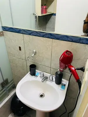a bathroom sink with a red blow dryer on it at El encanto de viajar in Lima