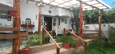 a house with a porch with potted plants in front of it at Hospedaje CASABLANCA URUBAMBA in Urubamba
