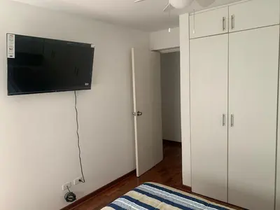 a bedroom with white cabinets and a flat screen tv at Departamento en Miraflores in Lima