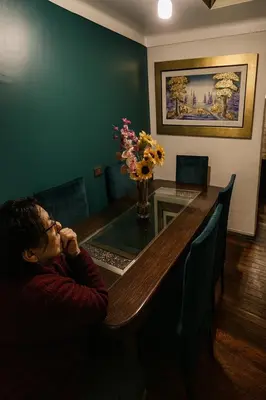 a person sitting at a wooden table with a dining room at Panay Golden in Cusco