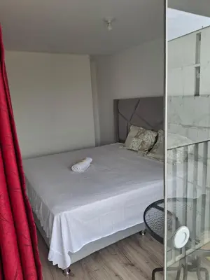 a small bedroom with a bed and a red curtain at Se alquila habitación con cama King y baño privado in Lima