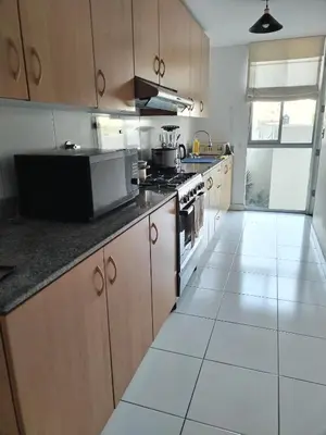 a kitchen with wooden cabinets and a white tile floor at Departamento en Miraflores, Lima 3HAB in Lima