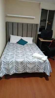 a bedroom with a bed with a blue pillow and a desk at Departamento en Miraflores, Lima 3HAB in Lima